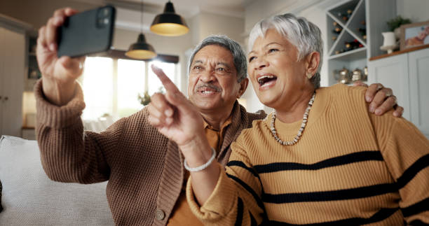 istock Senior couple, selfie and happy on sofa, hug or talking for choice, check post and point for photography in home. Elderly woman, man and laugh with profile profile, web blog and social media on couch 2150854973