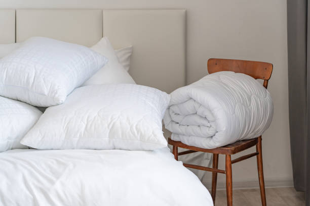 istock A bed with white pillows and a blanket, next to a bedside table with a lamp, daylight 2150855473