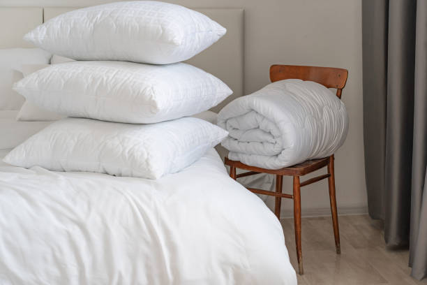 istock A bed with white pillows and a blanket, next to a bedside table with a lamp, daylight 2150855476