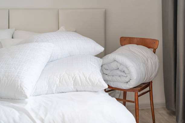 istock A bed with white pillows and a blanket, next to a bedside table with a lamp, daylight 2150855479