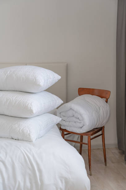 istock A bed with white pillows and a blanket, next to a bedside table with a lamp, daylight 2150855480