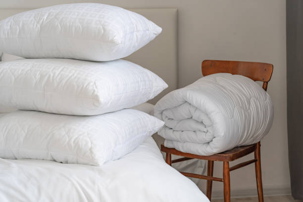 istock A bed with white pillows and a blanket, next to a bedside table with a lamp, daylight 2150855487