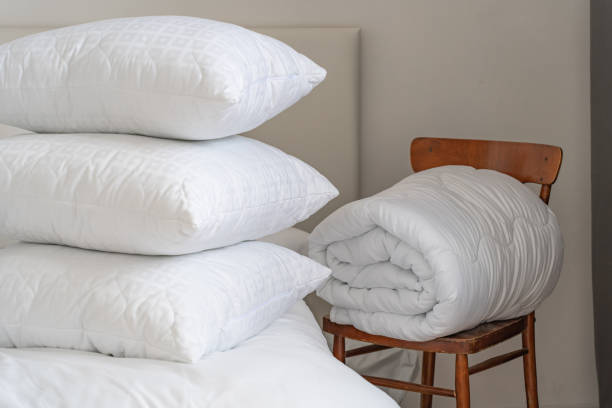 istock A bed with white pillows and a blanket, next to a bedside table with a lamp, daylight 2150855494