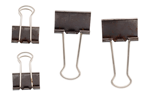 Rusty old black metal paper clips isolated on white