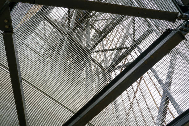 New modern tall metal construction observation tower with transparent steel grid floors, bottom up view, geometric shape background