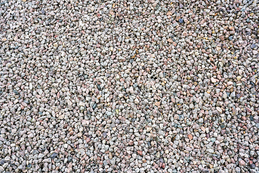Closeup of abstract colorful grey fine granite gravel pebbles, background of gravel surface texture, crushed gravel texture