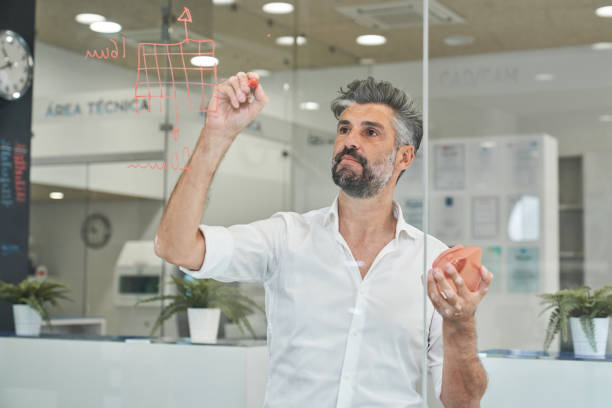 istock Focused man writing on glass while designing model of respirator 2150860374