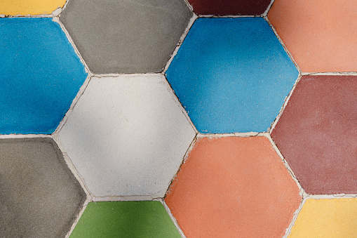 A colorful mosaic tile pattern with a variety of colors. The tiles are arranged in a hexagonal shape, creating a visually appealing and unique design. Scene is vibrant and lively