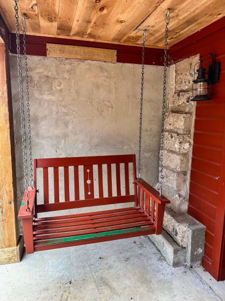 istock Cute red wooden swing on back porch with lantern style hanging light 2150861732