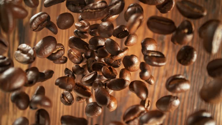 Super Slow Motion of Falling Coffee Beans on Wooden Table.