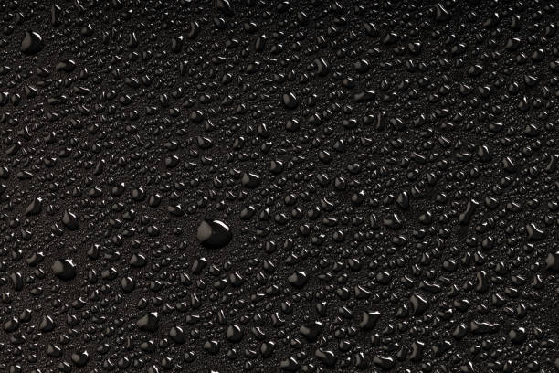 istock a large drop of water around which small drops on a black plastic surface 2150868173