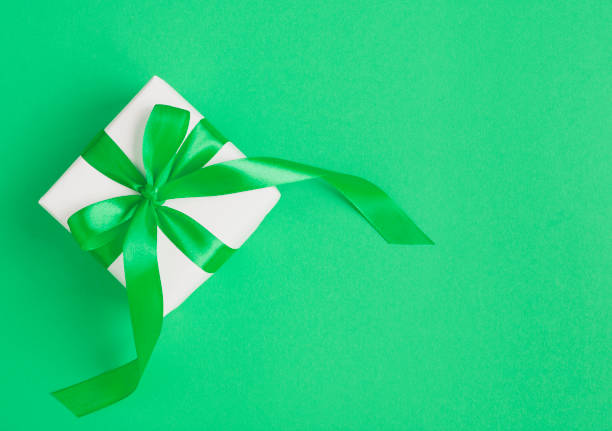 Green present on white background with customizable space for text. Copy space and celebration.