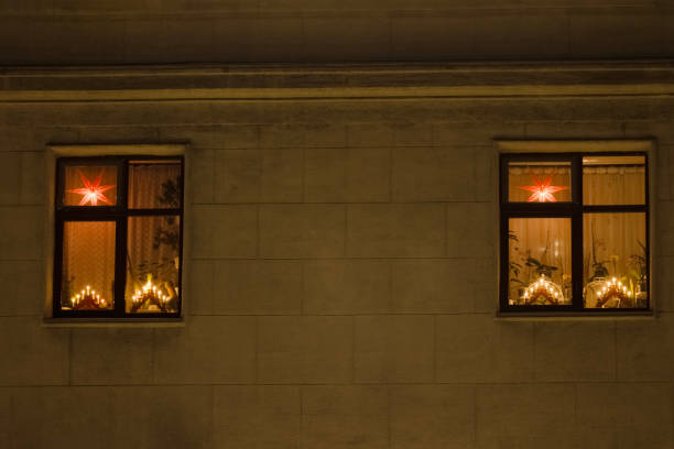 two illuminated windows in an old house decorated with burning holiday lights for Christmas