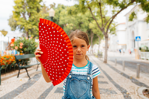 Beautiful girl holding red hand fan and posing in front of famous  wooden achitecture structure building Metropol Parasol in Seville Spain