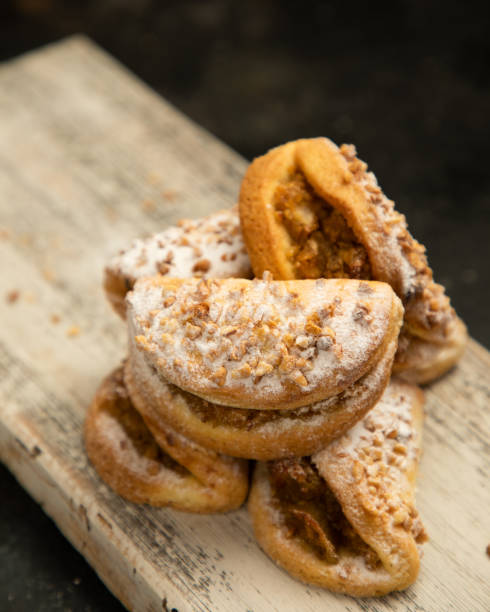 A stack of pastries with a lot of powdered sugar on top. The pastries are piled on top of each other on a wooden table