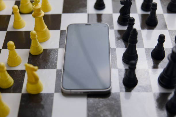 istock Smartphone with black and white chess pieces on a chessboard 2150876306