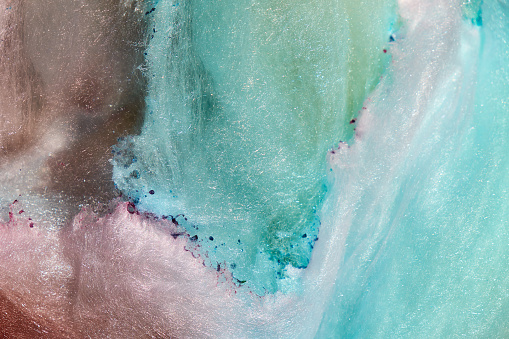 Close-up photo of a soft and fluffy pink and blue cotton candy, evoking a sense of dreamy abstraction.