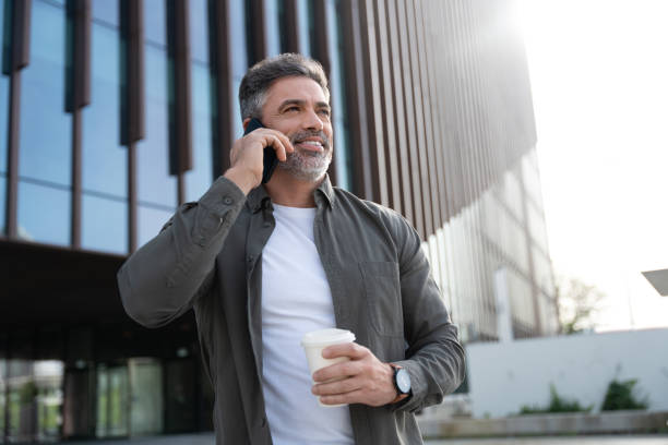istock 40s mature confident busy businessman entrepreneur using cellphone mobile phone for talking with family, business partners. Successful mid age man investor communicating on smartphone standing outdoor 2150877762