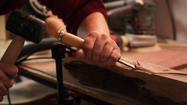 Manufacturer in studio shaping wooden pieces with tools, close up Craftsperson carving into wood using chisel and hammer in carpentry shop with precision. Manufacturer in studio shaping wooden pieces with tools, making wood art, camera A close up shot art and craft product stock pictures, royalty-free photos & images