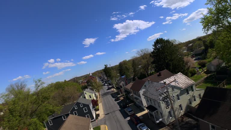 FPV drone shot over American town street during bright day. Fast flying with angled horizon.