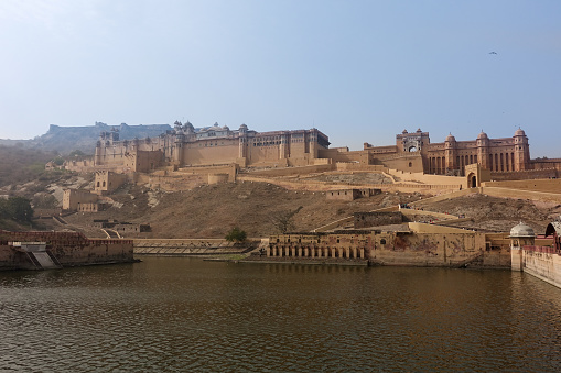Overview of the outside walls of Amber Fort located high on a hill with Jaigarh Fort in the background in Jaipur, Rajasthan, India.