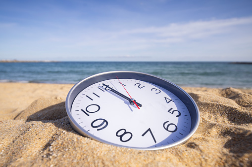 a clock passing time on a beach