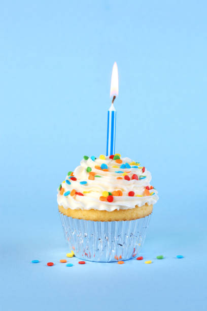 istock Iced birthday cupcake with with lit candle and sprinkles 2150887050
