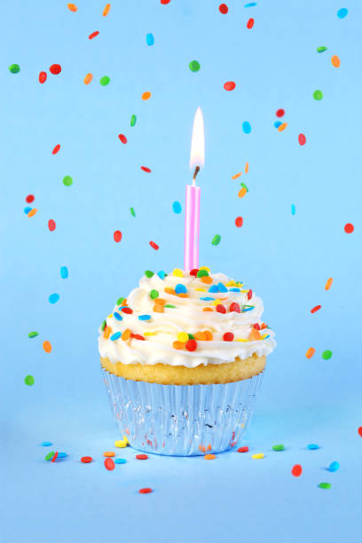 istock Iced birthday cupcake with with lit candle and sprinkles 2150887078