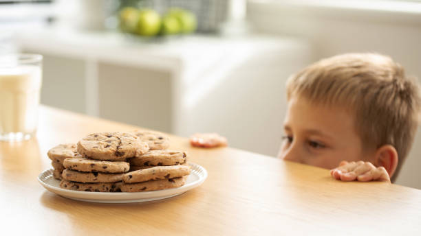 istock A boy is peeping at an appetizing stack of freshly baked chocolate cookies on the table. 2150888886