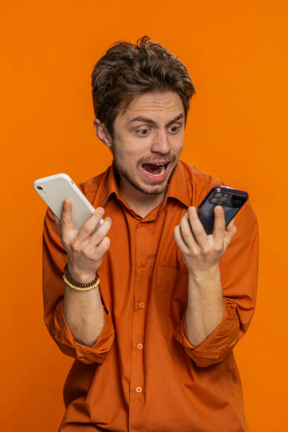 istock Irritated stressed business man talking on two mobile phones having conversation conflict quarrel 2150890187
