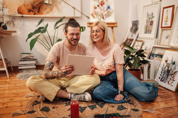 istock Creative artist couple sitting on floor at studio and looking at artwork 2150890317