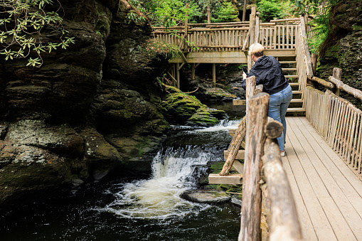 Woman, tourist taking photos of natural point of interest - Bushkill Falls at Pocono Mountains in Pennsylvania