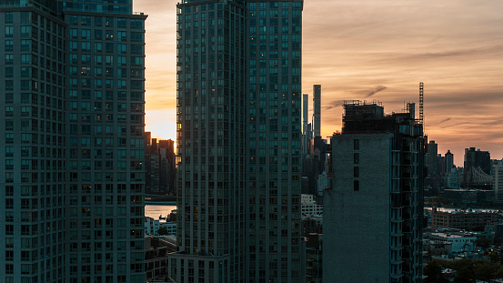 Modern apartments of Hunters Point, Long Island, Queens, with remote Manhattan seen through the towers at sunset.
