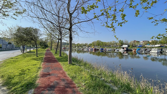 Kucukcekmece,istanbul,Turkey.April 13,2024. Menekse stream, which connects the Marmara Sea and Kucukcekmece lake. Nature view with boats on the stream and the park and walking paths around it.