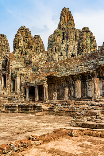 Mysterious ruins of ancient Bayon temple in Angkor Thom. Amazing Angkor Thom nestled among rainforest in Siem Reap, Cambodia. Enigmatic Angkor Thom is a popular tourist attraction.