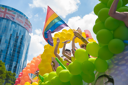Mexico City, parade LGBT community México City. 08/07/2019 A group of people are holding rainbow balloons and a flag, and are standing in front of a building