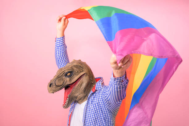 istock man with T rex head waves a rainbow flag on an isolated pink background. surreal and fun concept 2150913056