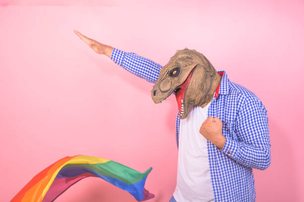 istock man in dinosaur mask with funny pose with a rainbow flag on isolated pink background 2150913087