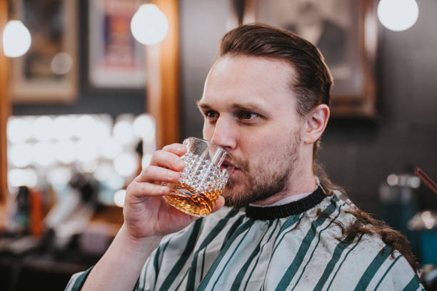 istock Man drinks a glass of scotch while in a trendy barber shop 2150914320