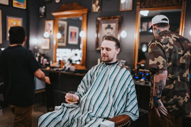 istock Man holds a glass of scotch while getting a haircut 2150914323