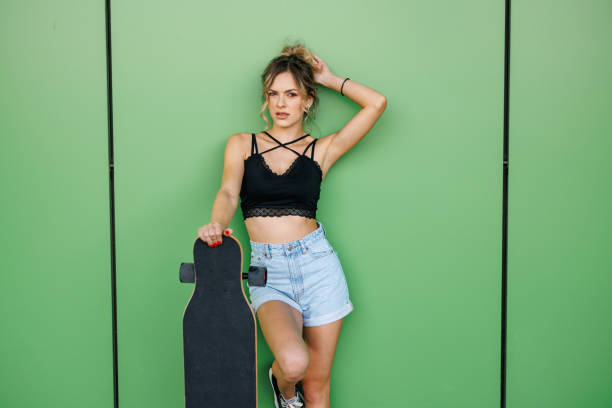 istock Young female skater posing on green background 2150914782