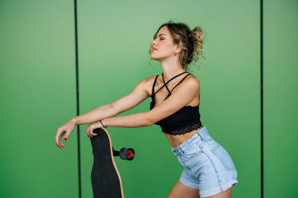 istock Young female skater posing on green background 2150914907