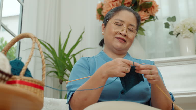 elderly Asian woman spends her free time crocheting as a hobby.