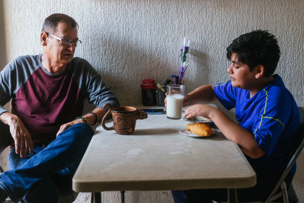 Photo of a grandfather sharing coffee and breakfast with his grandson at a plastic table with a coffee cup