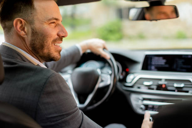 istock Smiling man enjoying a sunny drive in a modern car interior 2150918679