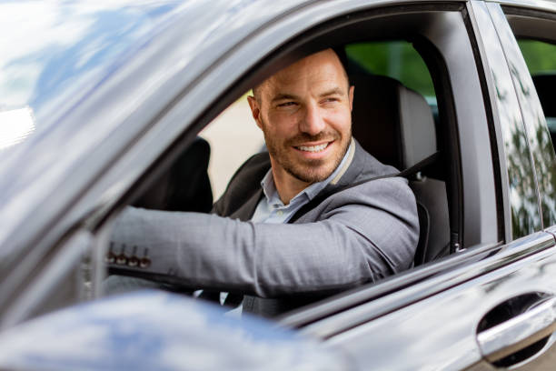 istock Smiling man enjoying a sunny drive in a modern car interior 2150918684