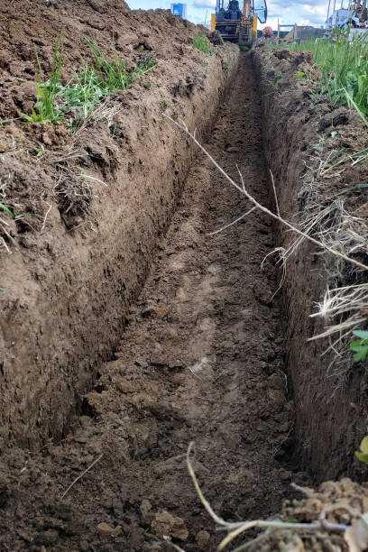 istock Construction excavator digging a shallow groove for electrical wiring or cable. 2150920422