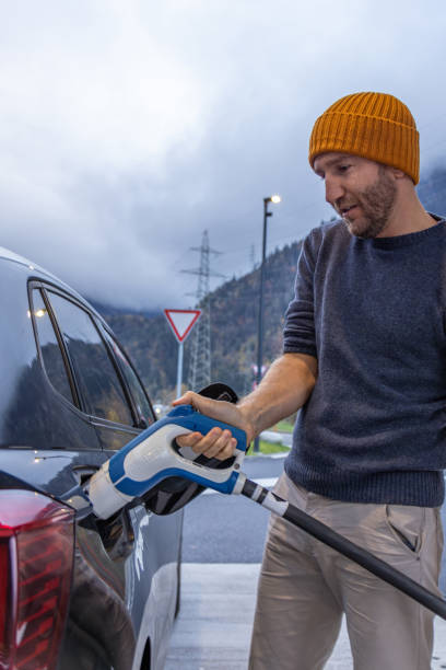istock Man charges electric vehicle at a public charging station 2150920645