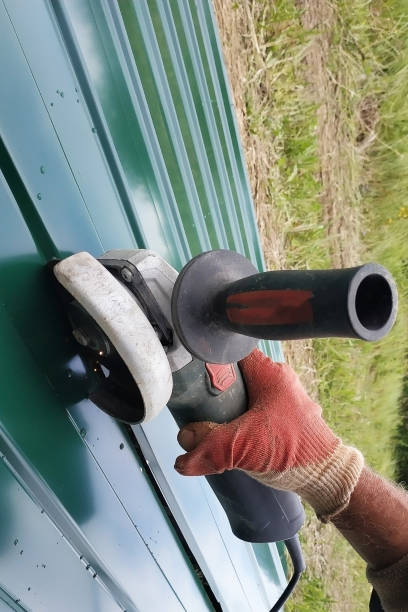 istock Worker cuts a metal sheet with an angle grinder outdoors in the village. 2150921392