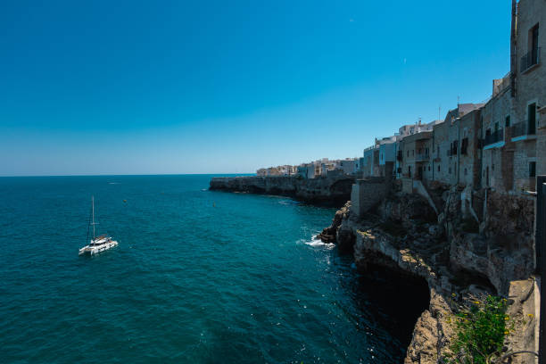 istock Catamaran boat floating next to Polignano a Mare beachfront at old town. Beautiful coastal town in Apulia is being attracted to many tourists. 2150923778